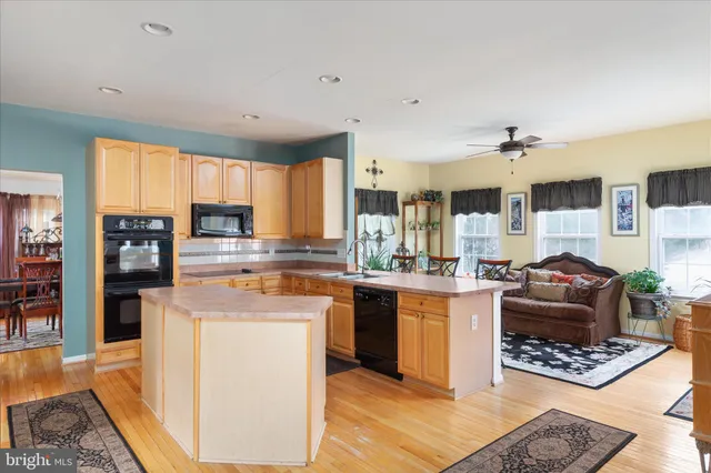 a kitchen with stainless steel appliances kitchen island granite countertop a refrigerator a stove top oven a sink dishwasher and white cabinets with wooden floor