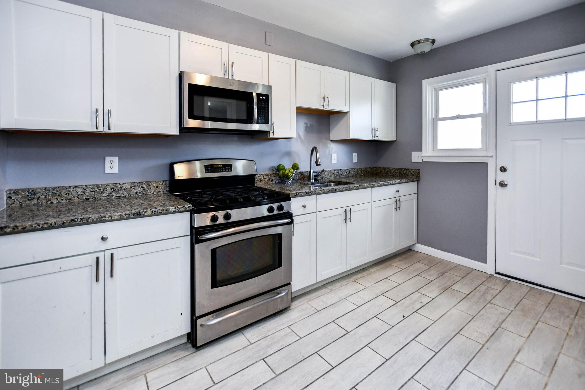 1028 Evesham Avenue Baltimore, MD 21212 - Photo 16 of 49 a kitchen with granite countertop white cabinets stainless steel appliances and window