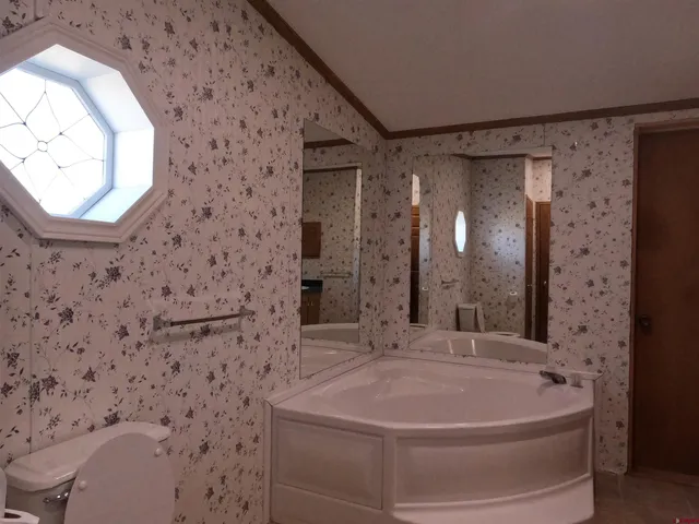 a view of a room that has a large window and wooden floor