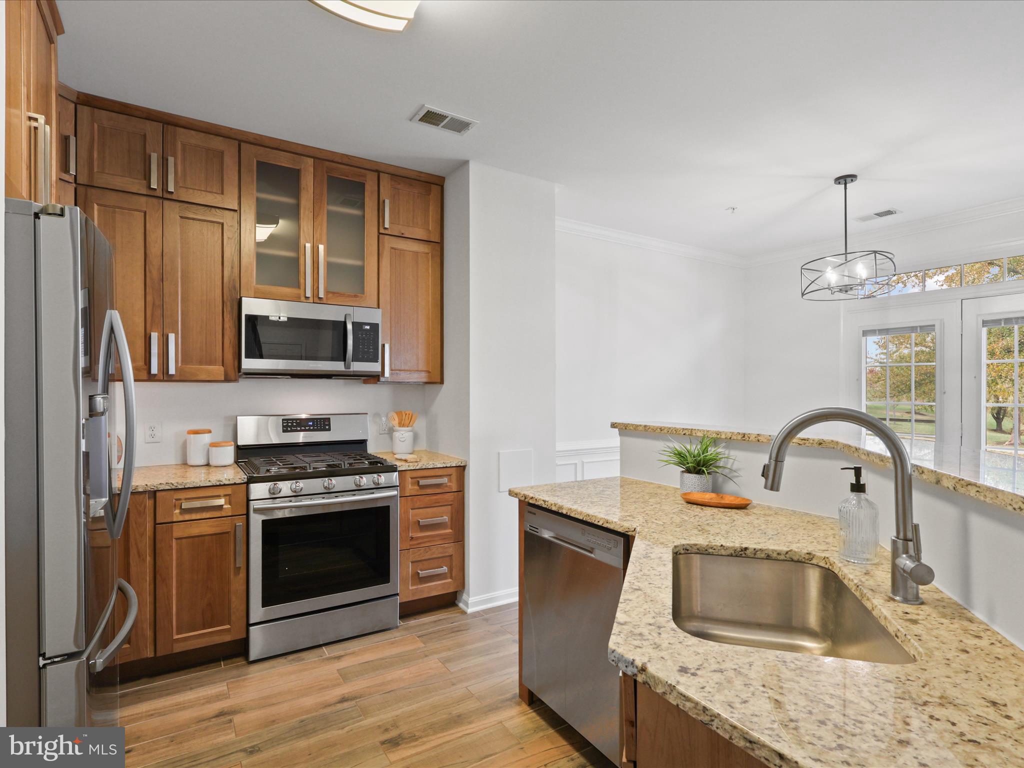 14592 Kylewood Way Gainesville, VA 20155 - Photo 10 of 60 a kitchen with stainless steel appliances granite countertop a sink dishwasher stove and microwave with wooden floor