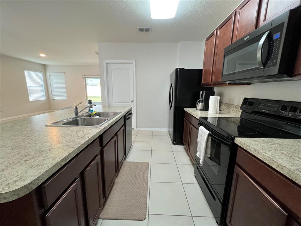 1756 Brockridge Road Kissimmee, FL 34744 - Photo 13 of 26 a kitchen with stainless steel appliances granite countertop a sink stove microwave and refrigerator