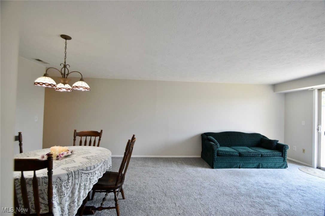 8955 West Ridge Road, Unit D Elyria, OH 44035 - Photo 15 of 33 Dining area with carpet flooring, a textured ceiling, and a chandelier