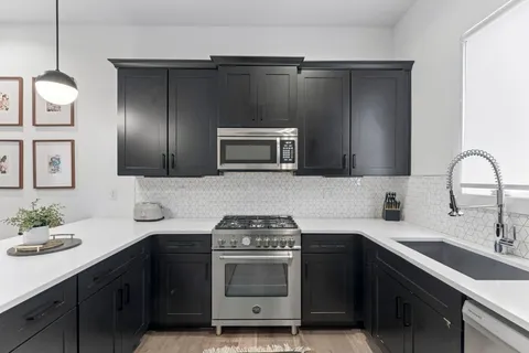 a kitchen with a sink and a stove top oven with wooden floor