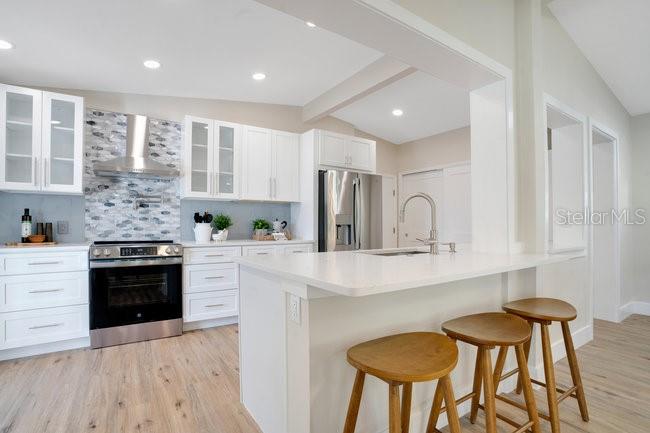 1926 Natalen Road Winter Park, FL 32792 - Photo 13 of 44 a kitchen with stainless steel appliances kitchen island granite countertop a stove a sink dishwasher and white cabinets with wooden floor