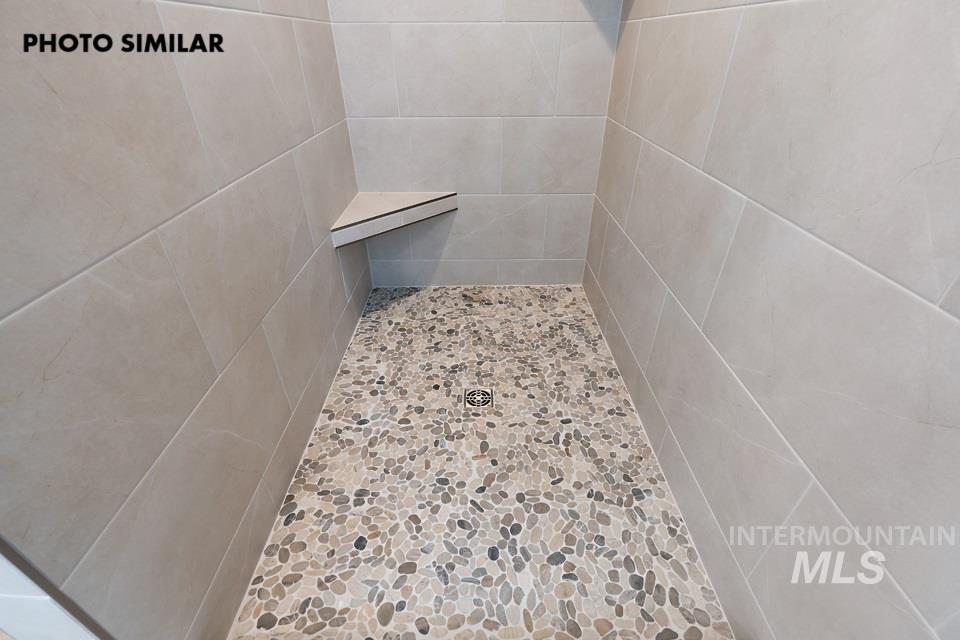 1645 Haystack Emmett, ID 83617 - Photo 19 of 33 Shower enclosure featuring light-toned rectangular wall tiles, pebble-style floor tiling, and a built-in corner shelf