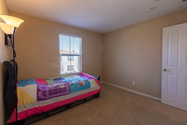 a bedroom with a bed and a lamp on dresser