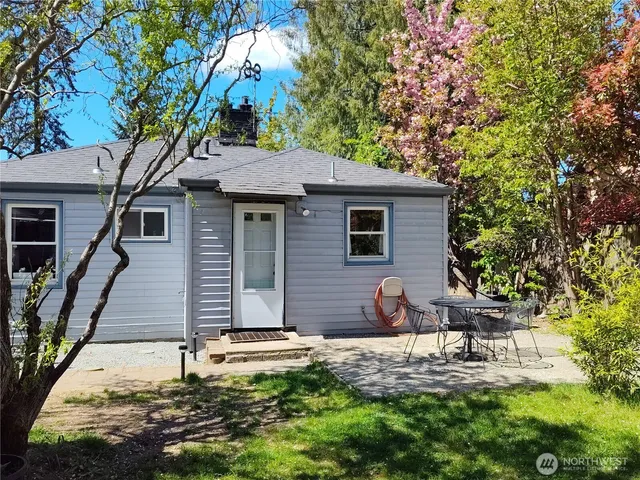 a backyard of a house with table and chairs large trees