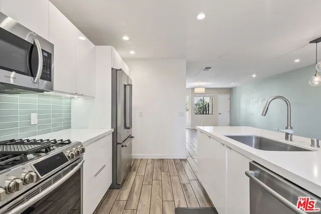 a view of an empty room with wooden floor and windows