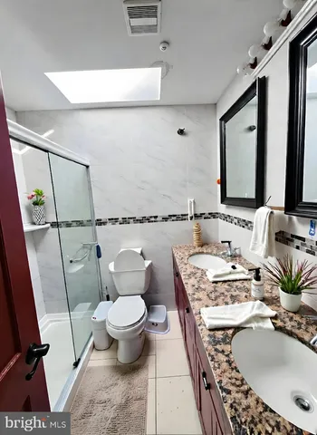a bathroom with a granite countertop sink mirror vanity and toilet