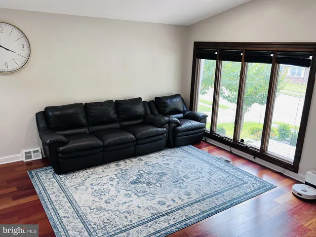 a living room with a couch floor to ceiling window and a rug
