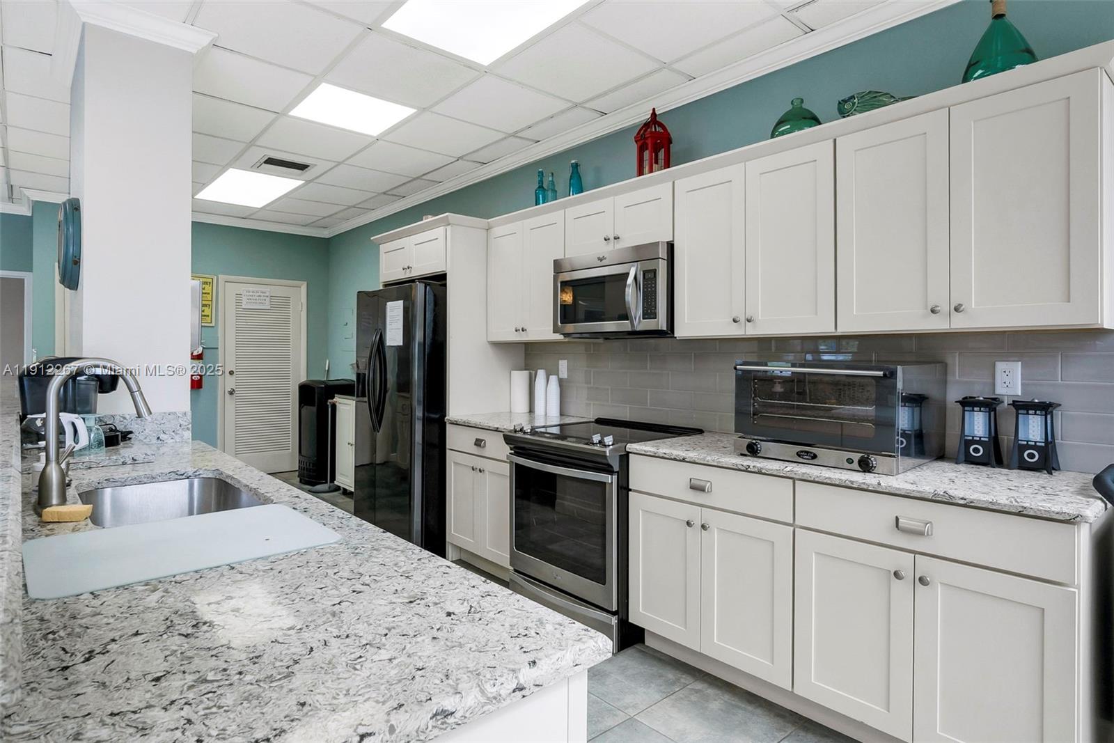 2121 North Ocean Boulevard, Unit 204W Boca Raton, FL 33431 - Photo 11 of 59 a kitchen with granite countertop a sink stainless steel appliances and white cabinets