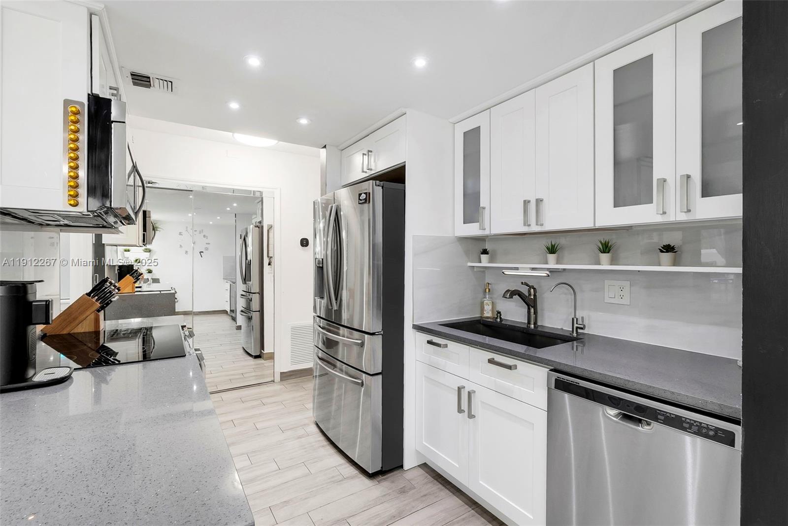 2121 North Ocean Boulevard, Unit 204W Boca Raton, FL 33431 - Photo 15 of 59 a kitchen with stainless steel appliances a refrigerator sink and cabinets