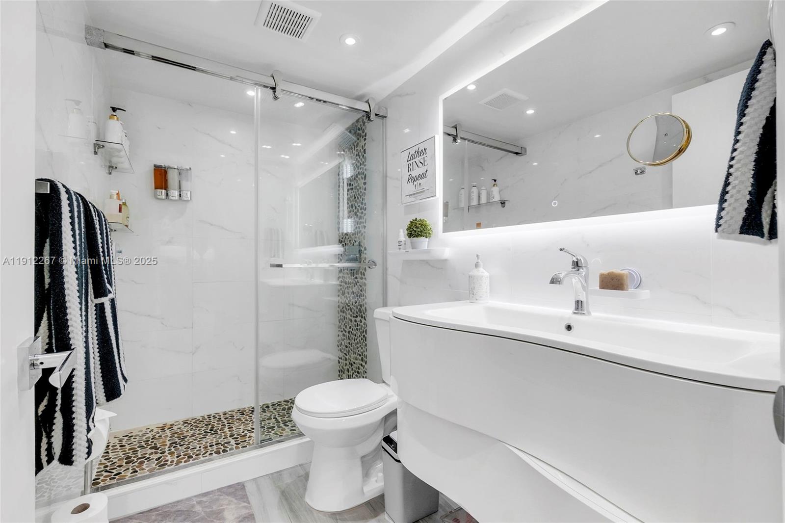 2121 North Ocean Boulevard, Unit 204W Boca Raton, FL 33431 - Photo 26 of 59 a bathroom with a sink a toilet and a large mirror