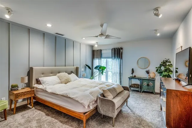 a bedroom with a bed table and a mirror