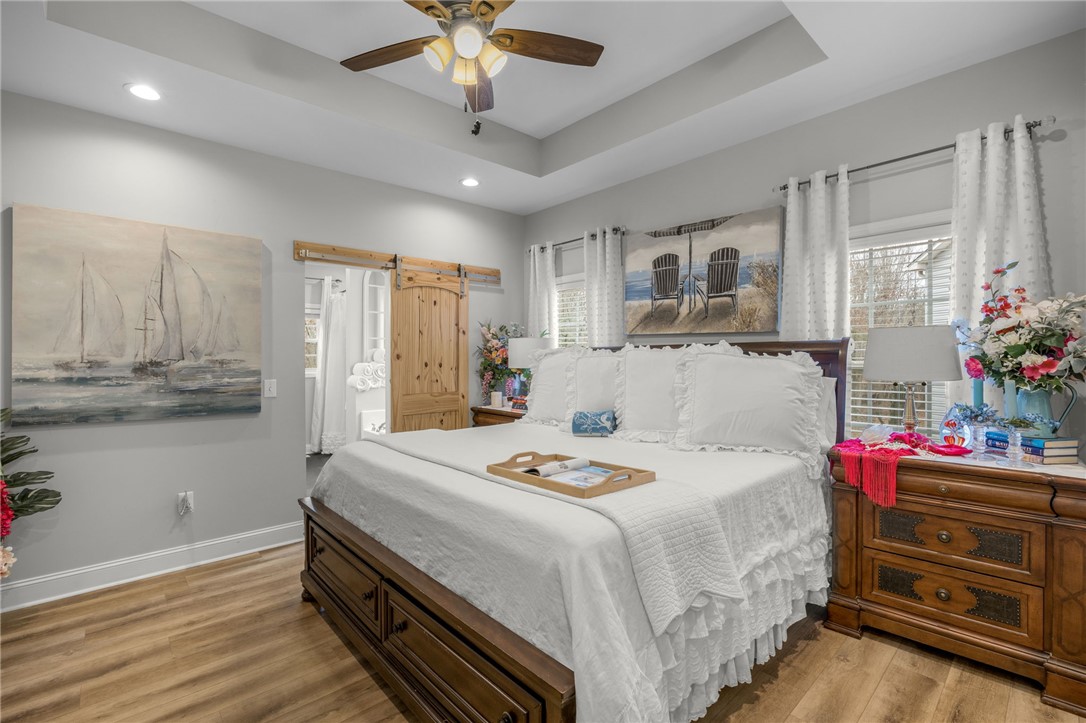 28 Vanessa Rae Lane Pendleton, SC 29670 - Photo 6 of 16 This spacious bedroom features a vaulted ceiling, wood flooring, and a unique barn door leading to an adjacent area.