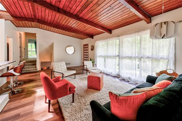 a living room with furniture a large window and wooden floor