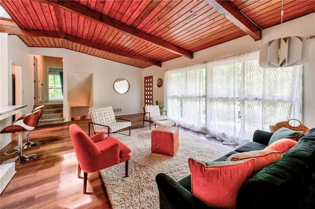 a living room with furniture a large window and wooden floor