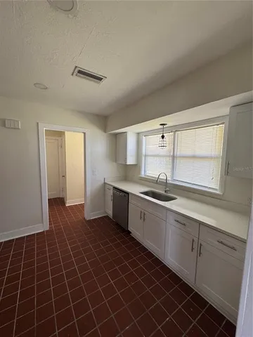 a large kitchen with granite countertop a sink a window and stainless steel appliances