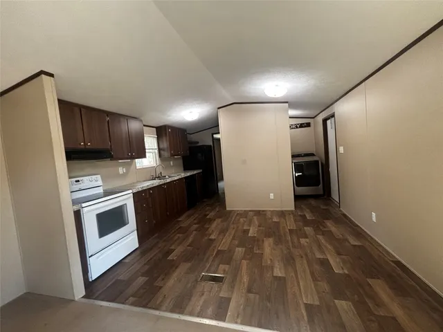 a kitchen with granite countertop a refrigerator and a stove top oven