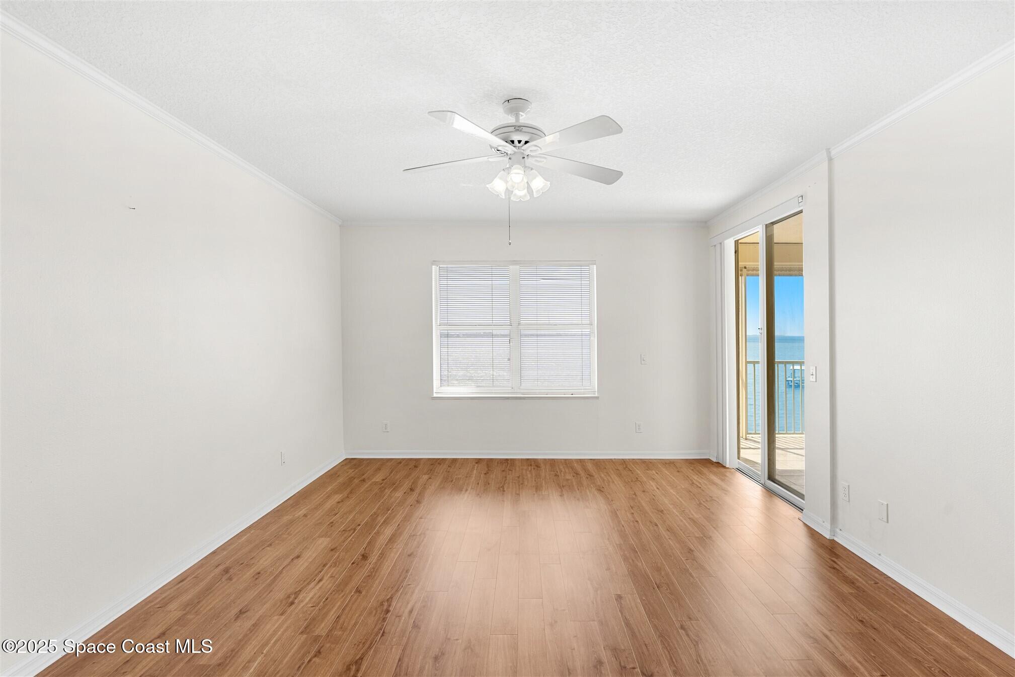 104 Riverside Drive, Unit 402 Cocoa, FL 32922 - Photo 14 of 41 an empty room with wooden floor chandelier fan and windows