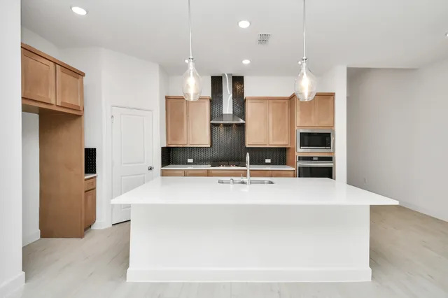 a kitchen with a sink chandelier and living room view