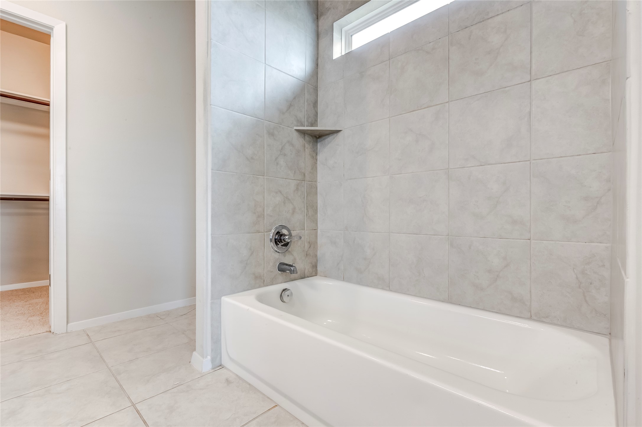 2721 Winding Creek Road Kyle, TX 78640 - Photo 19 of 27 Bathtub with light gray subway tile surround and integrated corner shelf