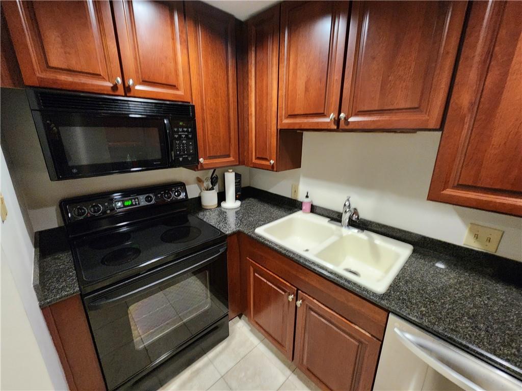 195 14th Street Northeast, Unit 304 Atlanta, GA 30309 - Photo 12 of 25 a kitchen with granite countertop wooden cabinets stainless steel appliances and a window
