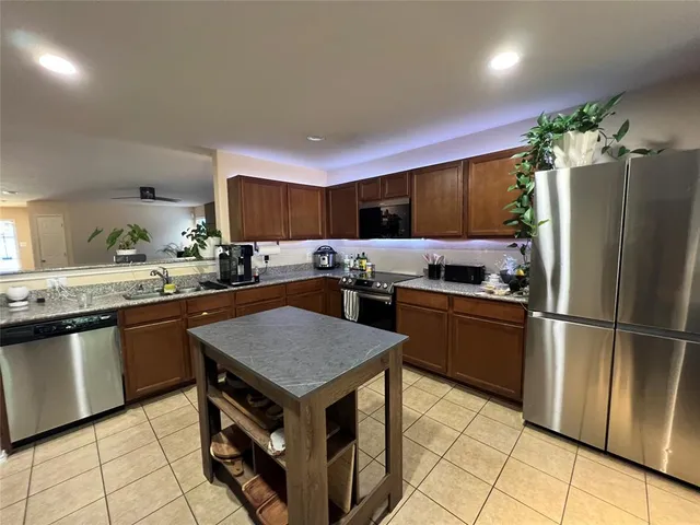 a kitchen with granite countertop a refrigerator stove top oven and sink