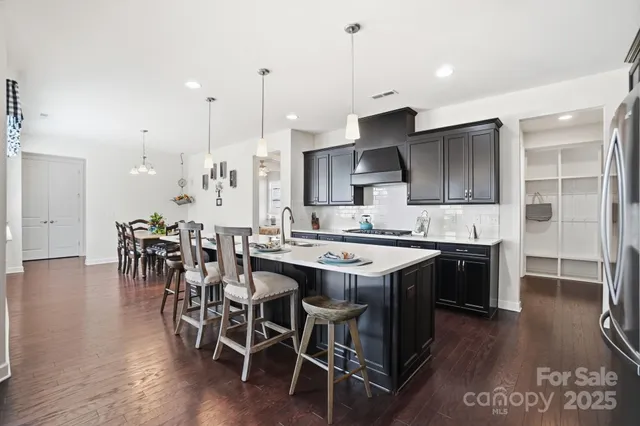 a kitchen with stainless steel appliances granite countertop a table chairs sink and cabinets