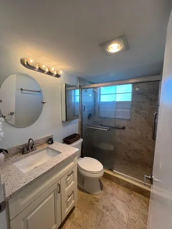 a bathroom with a granite countertop sink toilet and shower