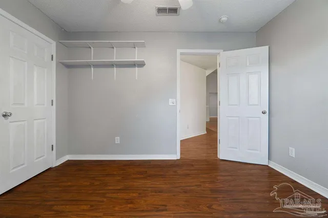 a view of an empty room with wooden floor and closet