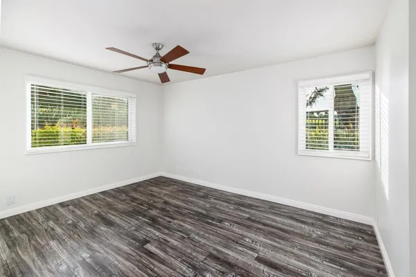 a view of empty room with wooden floor and fan