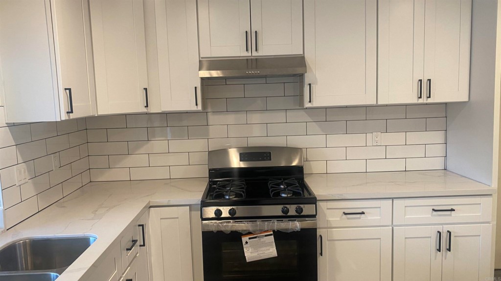 7780 Embry Point San Diego, CA 92126 - Photo 4 of 14 a kitchen with granite countertop white cabinets and white appliances