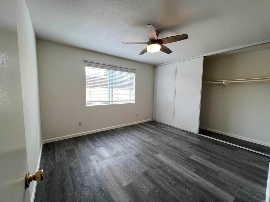 7780 Embry Point San Diego, CA 92126 - Photo 8 of 14 an empty room with wooden floor chandelier fan and windows