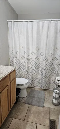 a bathroom with a granite countertop sink and a toilet