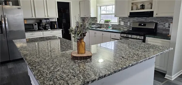 a kitchen with stainless steel appliances granite countertop a sink a stove and a wooden floors