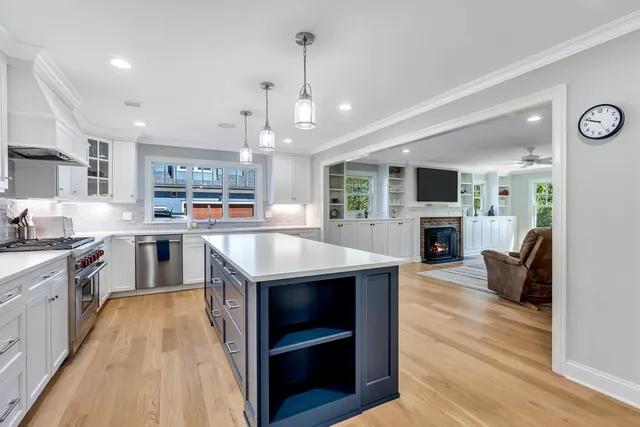 a kitchen with kitchen island granite countertop a stove top oven a sink dishwasher a dining table and chairs with wooden floor