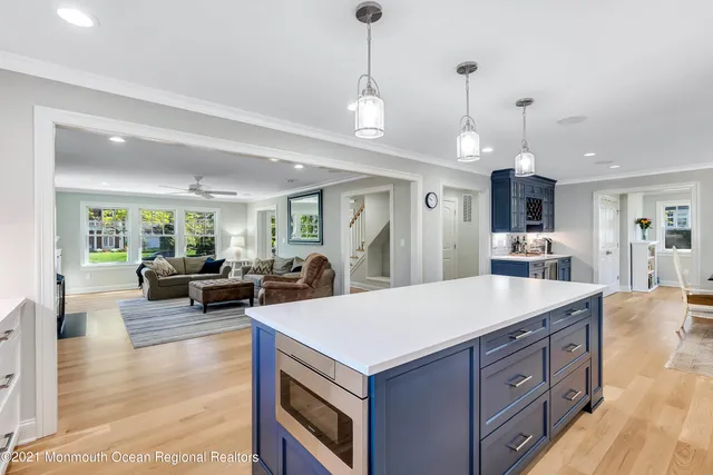 a large kitchen with stainless steel appliances kitchen island granite countertop a stove a refrigerator a sink a dining table and chairs with wooden floor