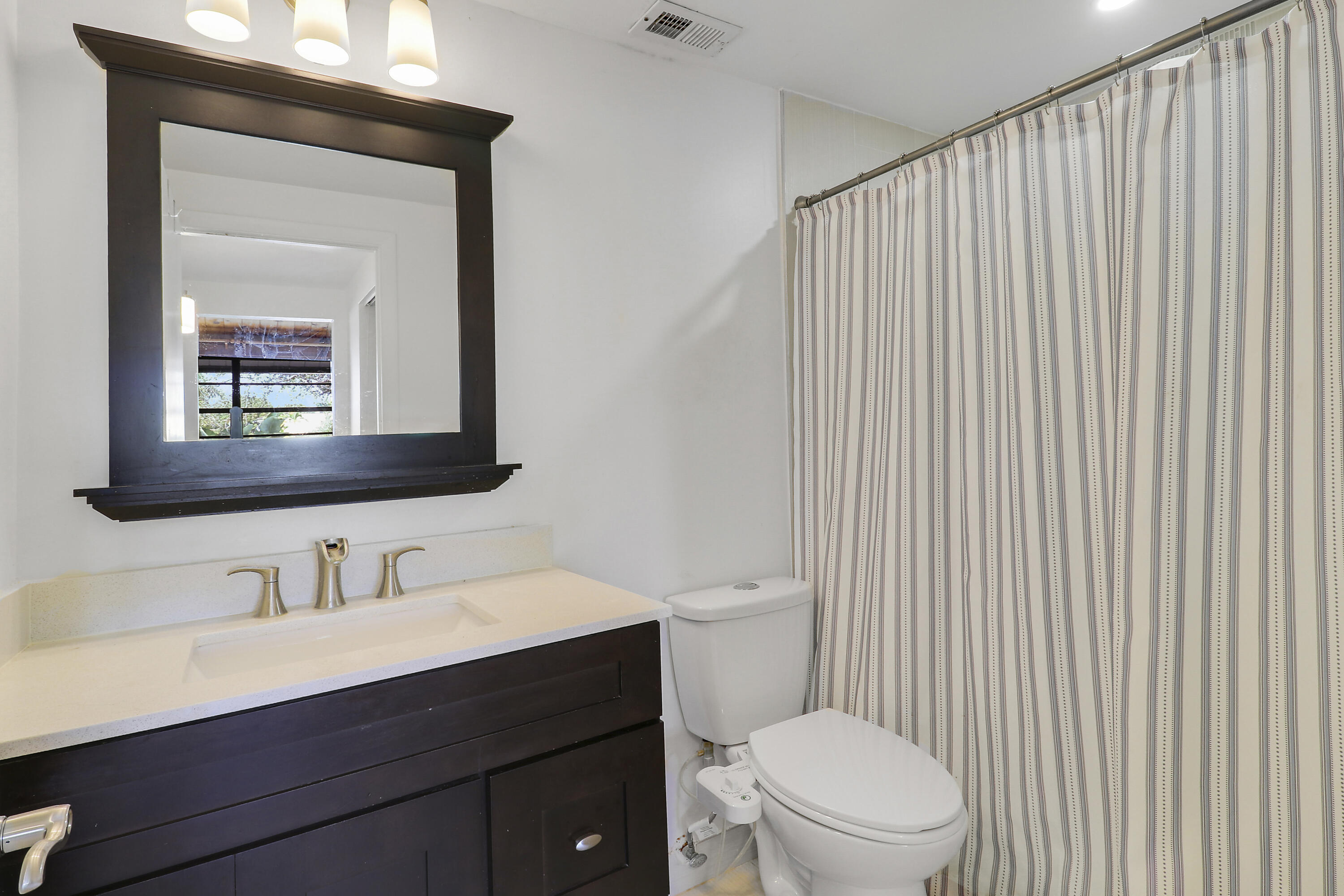 4801 Northwest 2nd Avenue, Unit 101 Boca Raton, FL 33431 - Photo 18 of 31 a bathroom with a toilet a sink a mirror and vanity