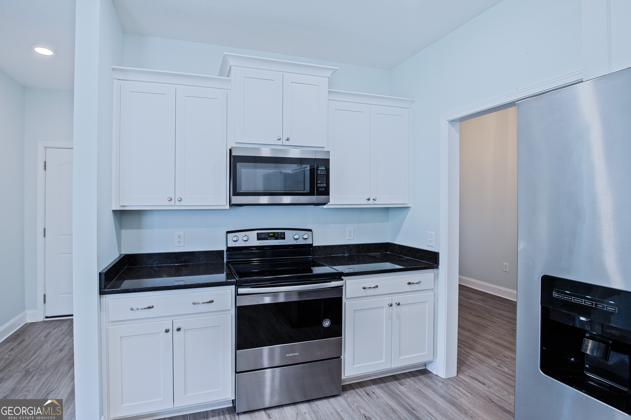 3453 John Wells Road Ludowici, GA 31316 - Photo 26 of 51 a kitchen with granite countertop white cabinets and black appliances