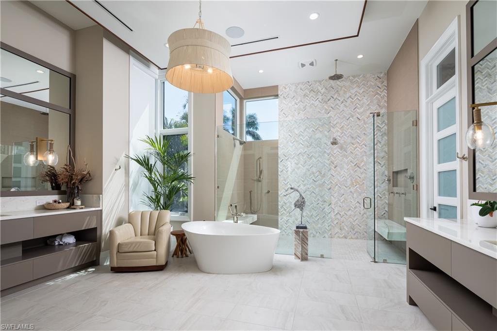 441 Mooring Line Drive Naples, FL 34102 - Photo 27 of 50 a spacious bathroom with a tub a double vanity sink a mirror a potted plant and a shower