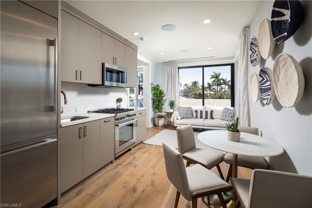 441 Mooring Line Drive Naples, FL 34102 - Photo 40 of 50 a kitchen with stainless steel appliances granite countertop a refrigerator a stove a sink a dining table and chairs with wooden floor