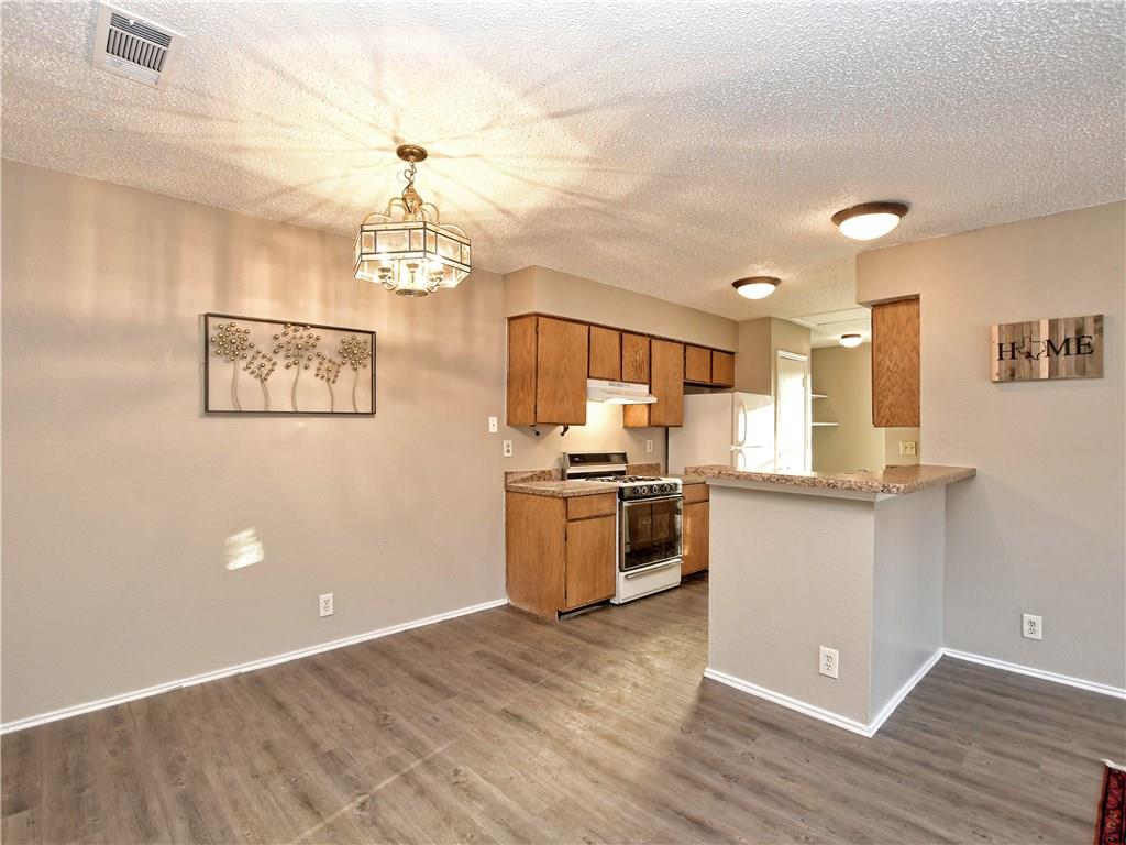 5401 Spring Meadow Road, Unit B Austin, TX 78744 - Photo 7 of 21 Durable plank flooring and a functional breakfast bar define this practical kitchen and dining area.