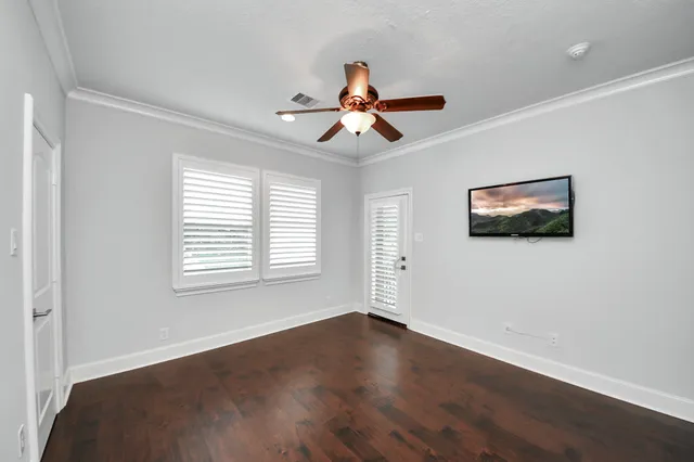 a view of empty room with wooden floor and fan
