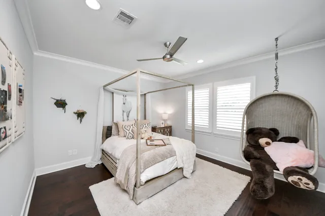 a bedroom with a bed a desk and chair with wooden floor
