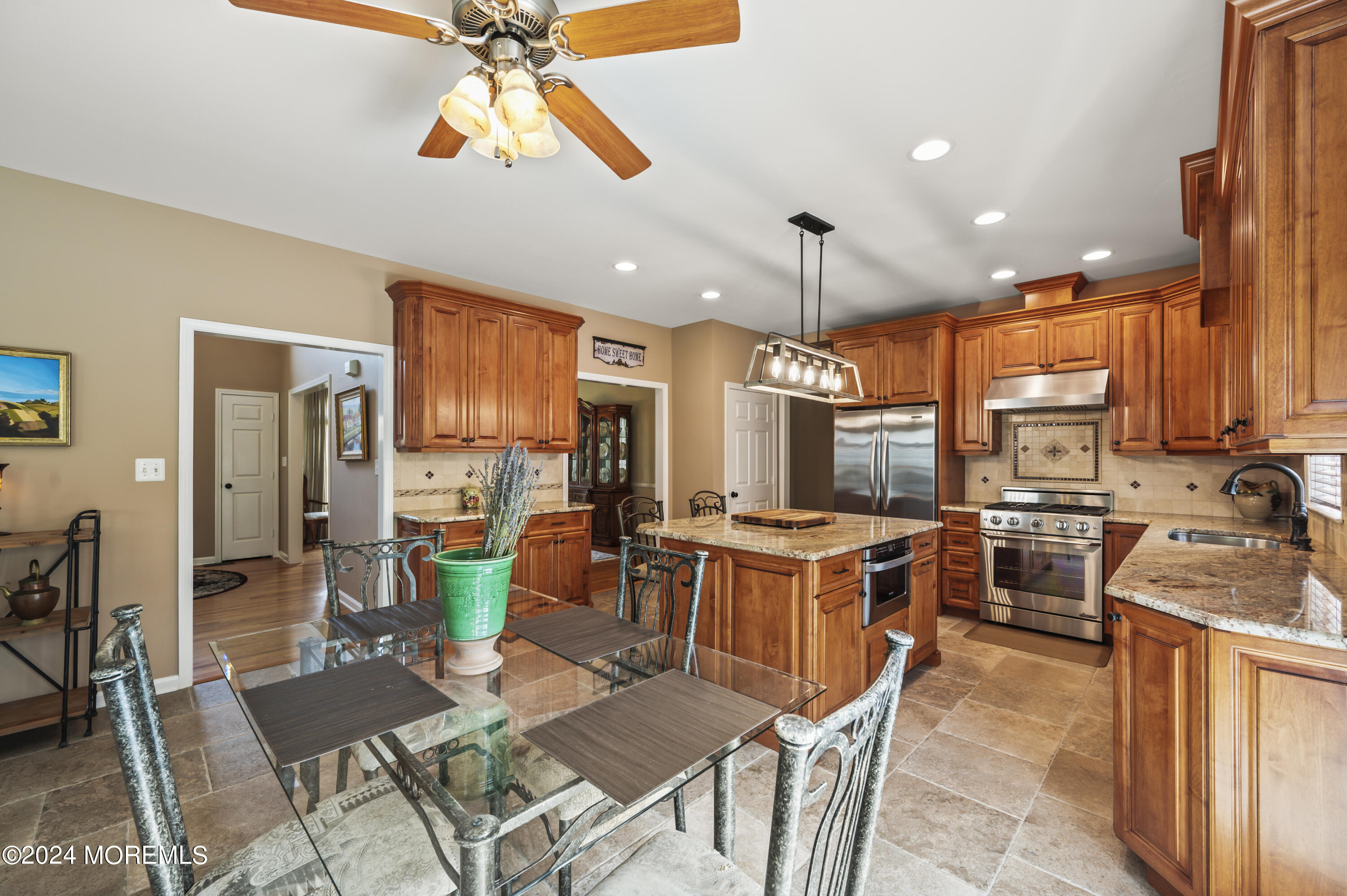 2805 Newman Way Wall, NJ 07719 - Photo 10 of 31 a kitchen with stainless steel appliances granite countertop a stove top oven a sink dishwasher a dining table and chairs with wooden floor