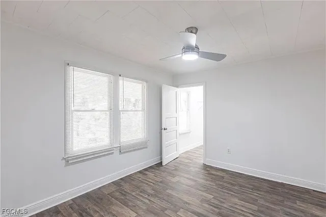 an empty room with wooden floor chandelier and windows