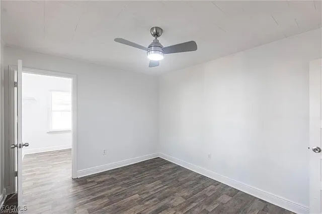an empty room with wooden floor and ceiling fan