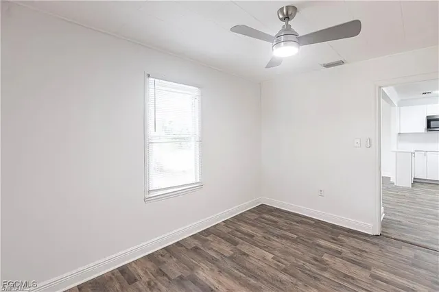 an empty room with wooden floor fan and windows