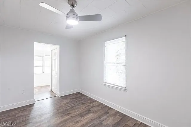 an empty room with wooden floor ceiling fan and windows